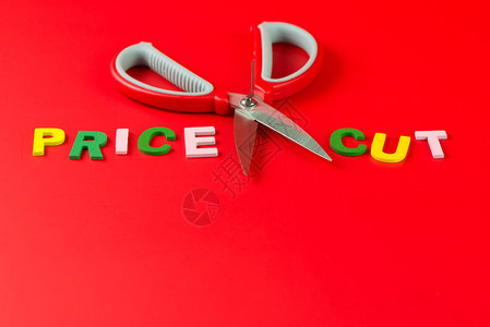 价格削减概念用一对剪刀在单价和红色背图片