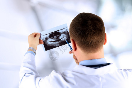男医生指着牙齿X光片的特写图片