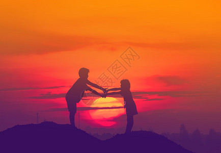 太阳落山时两个孩子手牵着手图片