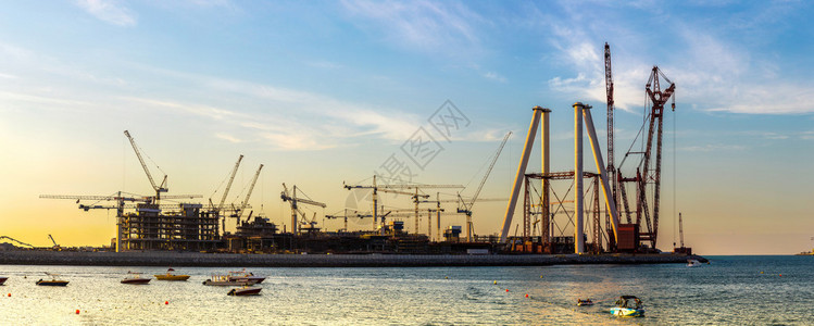 海上日落时迪拜建筑工地全景图片