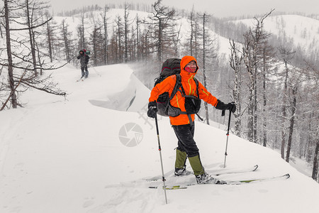 旅行者在阴天乘坐旅游滑雪板登上积雪覆盖的山峰图片
