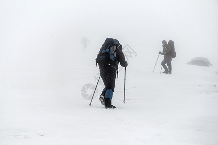 山上徒步群背着包和步行杆在冬季雪图片