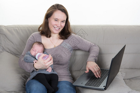 婴儿和忙碌的年轻女人拿着笔记本坐在房图片
