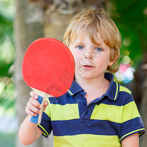 在家花园玩网球游戏的可爱滑稽小男孩图片