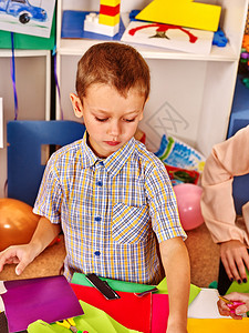 男孩在幼儿园的桌子上放着彩色纸学前习男孩为创意选择图片