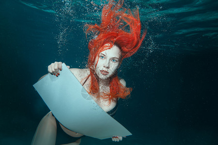 水下红头发的女人手里拿着一个牌子背景图片