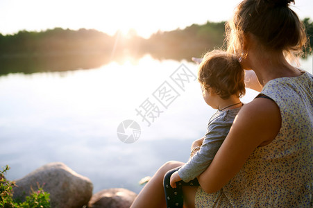 年轻怀孕母亲与儿子一起在湖边的夏图片