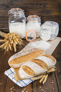 面包房桌上有小麦耳朵和面粉的酵母面包图片