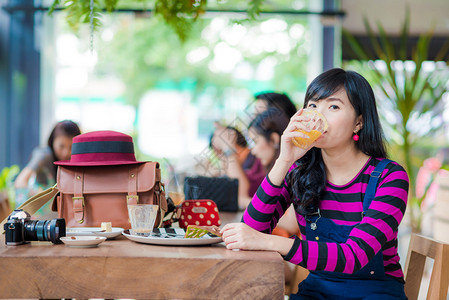 亚裔女子在美食咖啡厅喝橙汁美丽图片