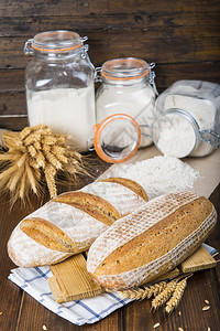 面包房桌上有小麦和面粉的酵母面包图片