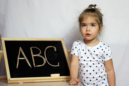可爱的小女孩想着在黑板前上学图片