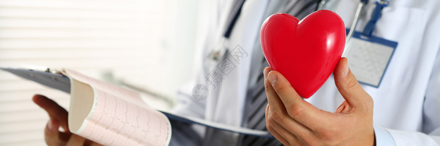 男医学生手握着剪贴板垫上的红色玩具心脏和心电图心脏治疗师医生制作心脏生理脉搏率测量心律失常概背景图片