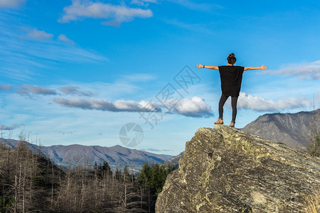 年轻女人站在山顶的岩石上站在图片