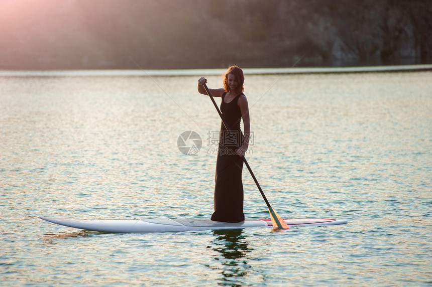 SUP穿黑裙子在水面上漂浮图片