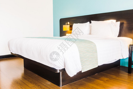 床上漂亮的豪华白色枕头和卧室内墙壁装饰上的灯图片