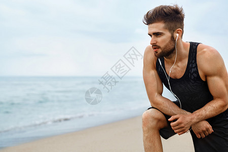 健壮的身体在海滩上慢跑后休息的健壮男子的画像图片