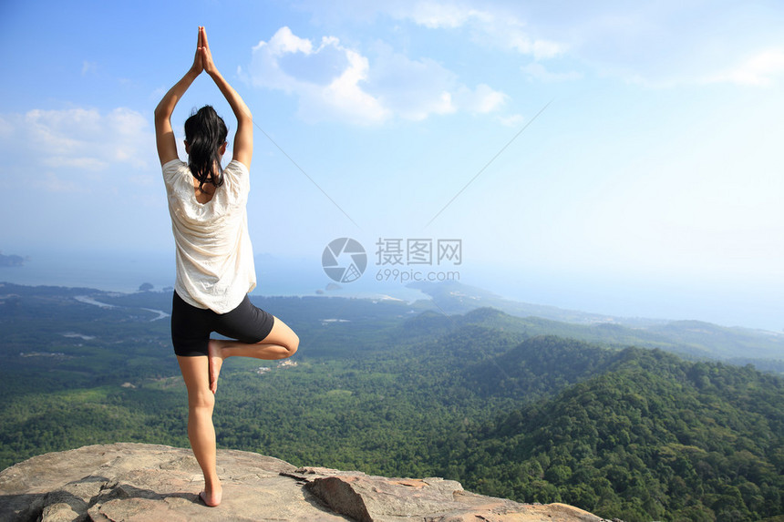 年轻健身女子在山峰悬崖练习瑜伽图片