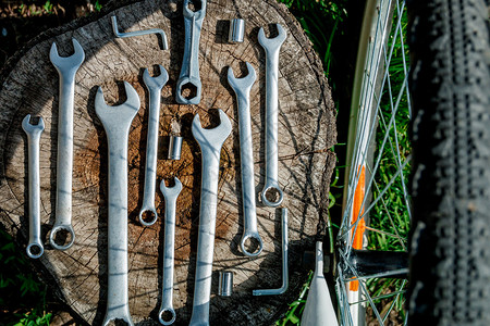 用于在靠近自行车轮的户外木制背景上修理自行车的仪器图片