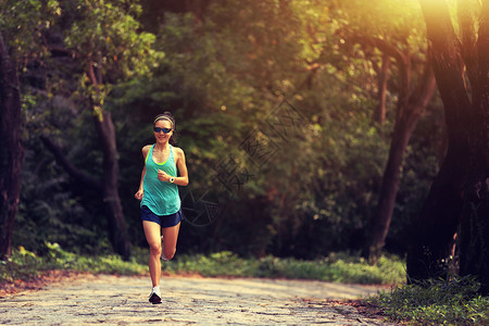 跑在森林里的年轻健身妇女越野跑者图片