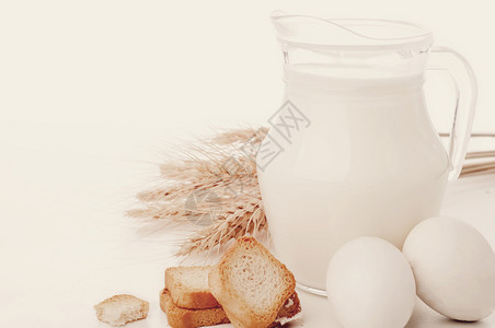 白色背景上装有牛奶小麦种子和两个的玻璃壶色调照片背景图片