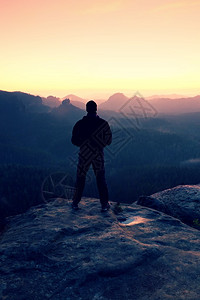在悬崖上高的黑人看着日出登山以自信作姿势做休眠图片