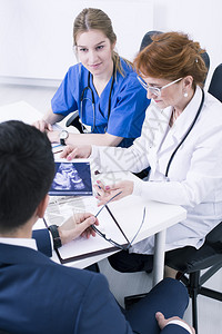 年轻漂亮的医生和年长的医生看着病人的USG照片在他们旁边图片
