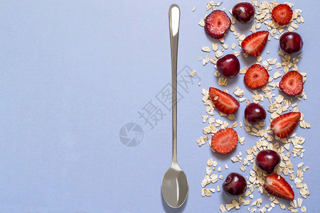 饮食和健康饮食的概念燕麦片配草莓和樱桃在蓝色背景上的边框与文本图片