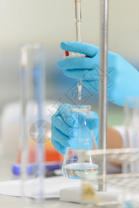 滴定管作为科学家的女人正在实验室里展示乳液技术的试验背景
