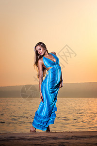 年轻美女穿着蓝色长裙站在沙滩图片
