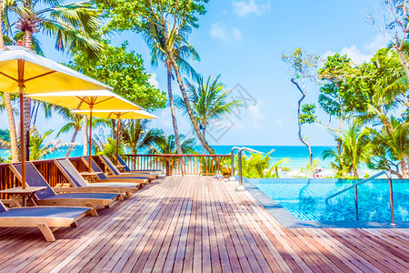 酒店度假村海滩和大海附近的游泳池周围美丽的豪华雨伞池和椅子图片