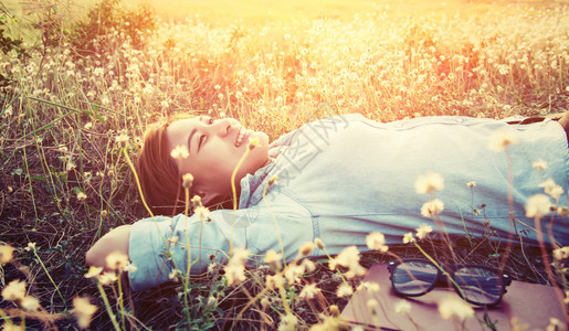 美丽的年轻嬉皮士躺在花朵田地上高清图片