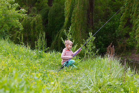 可爱的小男孩在河边钓鱼图片