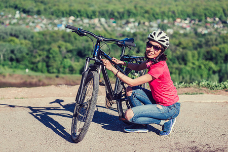 坐在自行车旁边检查一下的开心年轻女人图片