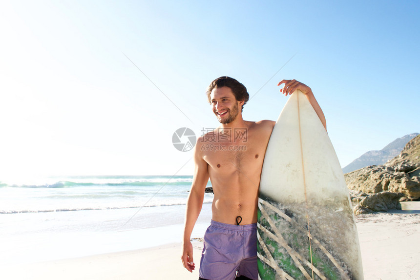 快乐的男冲浪者的肖像站在沙图片