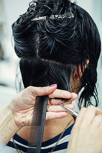 剪和梳子在沙龙里用剪刀和梳子理发女顾客的头发图片