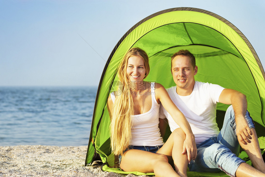 快乐的年轻夫妇在沙滩上露营图片