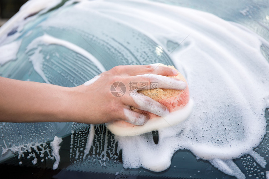 用海绵清洗车窗的男手的特写图片