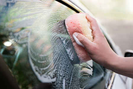 关闭男手握海绵和洗车窗的图片
