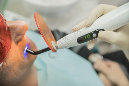 使用光聚合灯对牙科患者进行检查图片