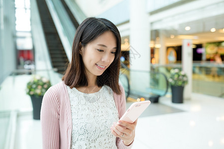 在购物中心使用移动电话的亚洲青年图片