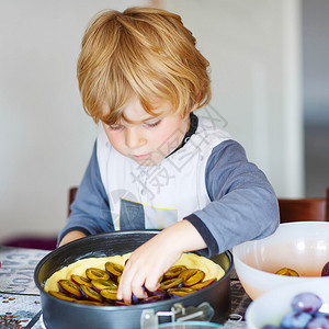 可爱的小男孩在室内的家用厨房里帮忙烤李子馅饼孩子用图片