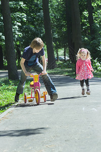 兄弟姐妹儿童通过跑步和骑三轮图片