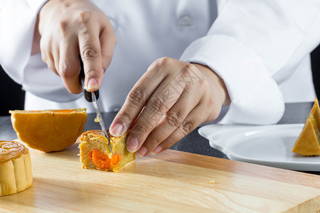 上菜月饼的厨师切菜是秋节的中式甜点图片