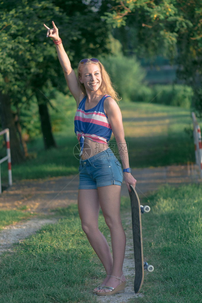 年轻的滑板女孩在户外用滑板摆姿势图片
