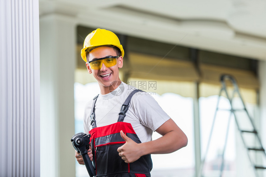 男人用钻孔器在墙上钻孔图片