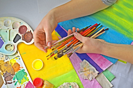 艺术家拿着画笔以艺术材料为背景图片