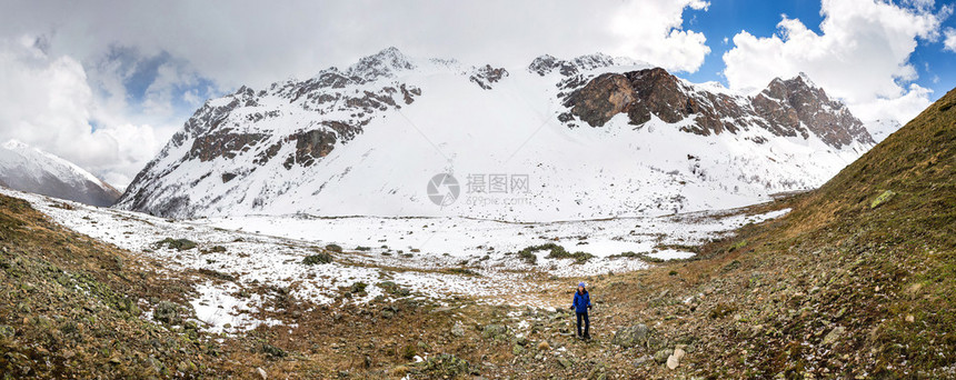 在雪地和冰川附近的山上行走的旅游远足者图片