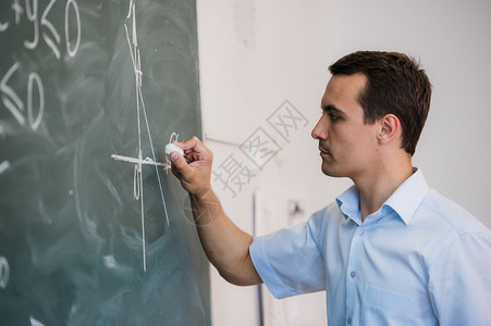 年轻的教师或学生在黑板上画三角图片
