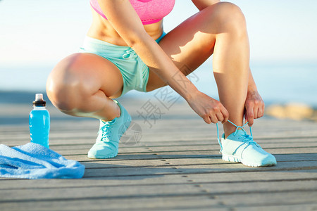 跑鞋系鞋带的女人女运动健身跑步者准备夏季在海滨户图片