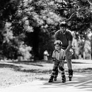 父亲带着儿子在公园溜冰的黑白形象图片